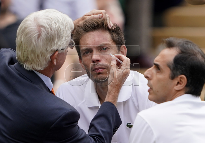 Nicolas Mahut (C) of France receives medical treatment during the Men's Doubles final match with Edouard Roger-Vasselin of France against Juan Sebastian Cabal of Colombia and Robert Farah of Colombia at the Wimbledon Championships at the All England Lawn Tennis Club, in London, Britain, 13 July 2019. EPA-EFE/NIC BOTHMA EDITORIAL USE ONLY/NO COMMERCIAL SALES