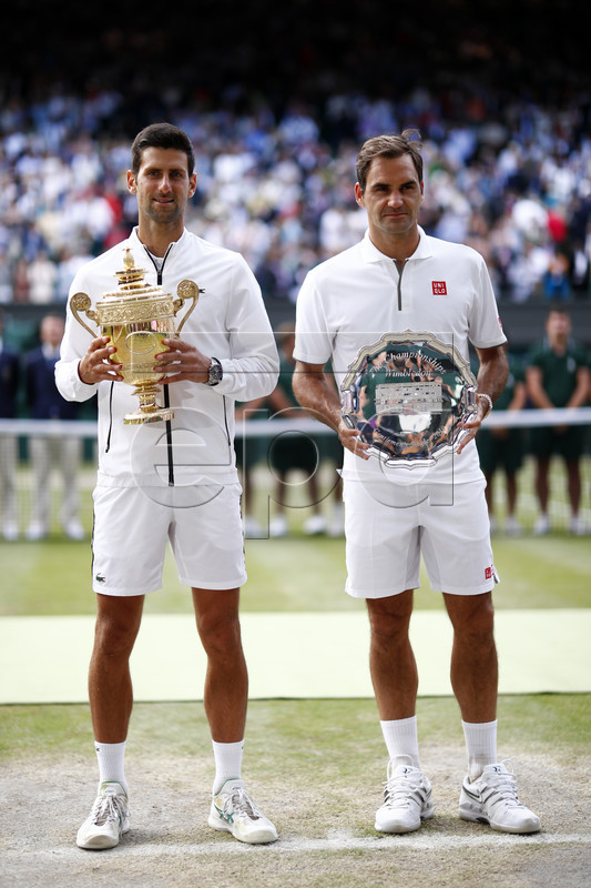 Novak Djokovic of Serbia (L) with the championship trophy after defeating Roger Federer of Switzerland (R) in the men's final of the Wimbledon Championships at the All England Lawn Tennis Club, in London, Britain, 14 July 2019. EPA-EFE/NIC BOTHMA EDITORIAL USE ONLY/NO COMMERCIAL SALES